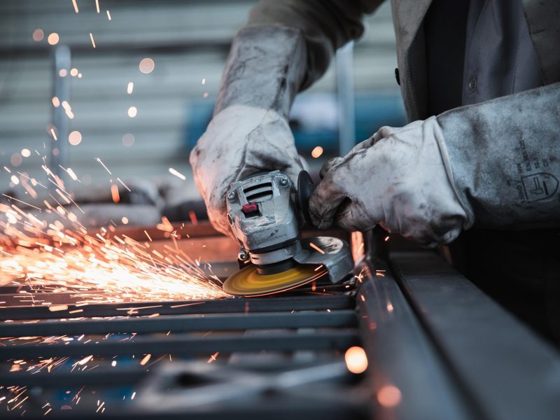 Person schleift Metall mit Winkelschleifer Person schleift Metall mit Winkelschleifer